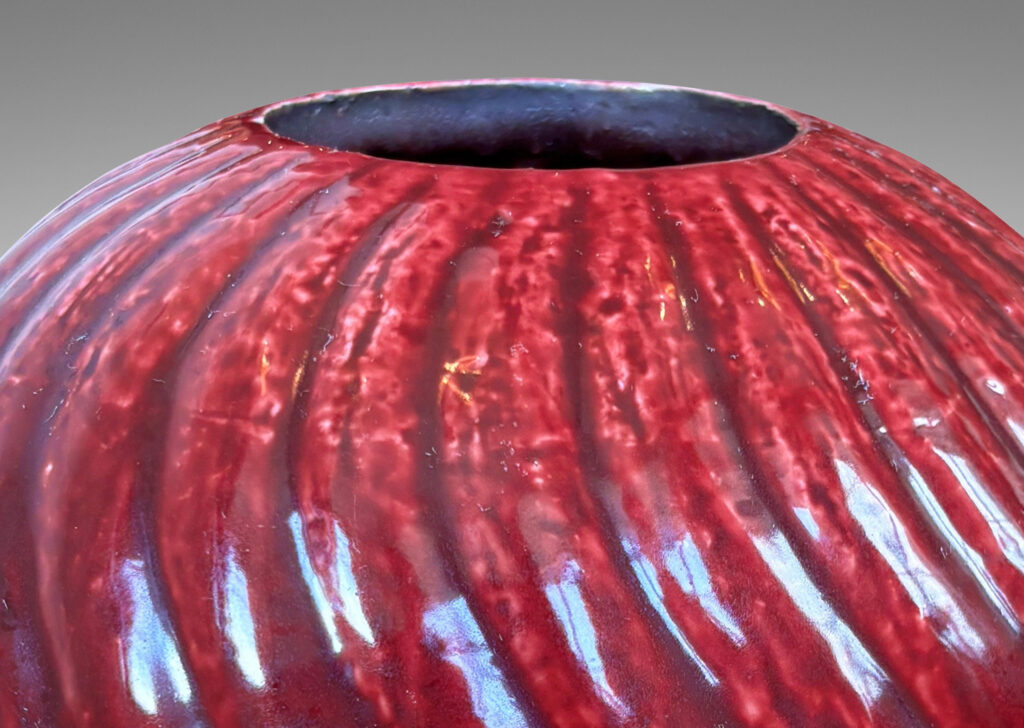 Gallery BAC globe form with spiraling vertical ribbing, in textured chamotte with a burgundy glaze