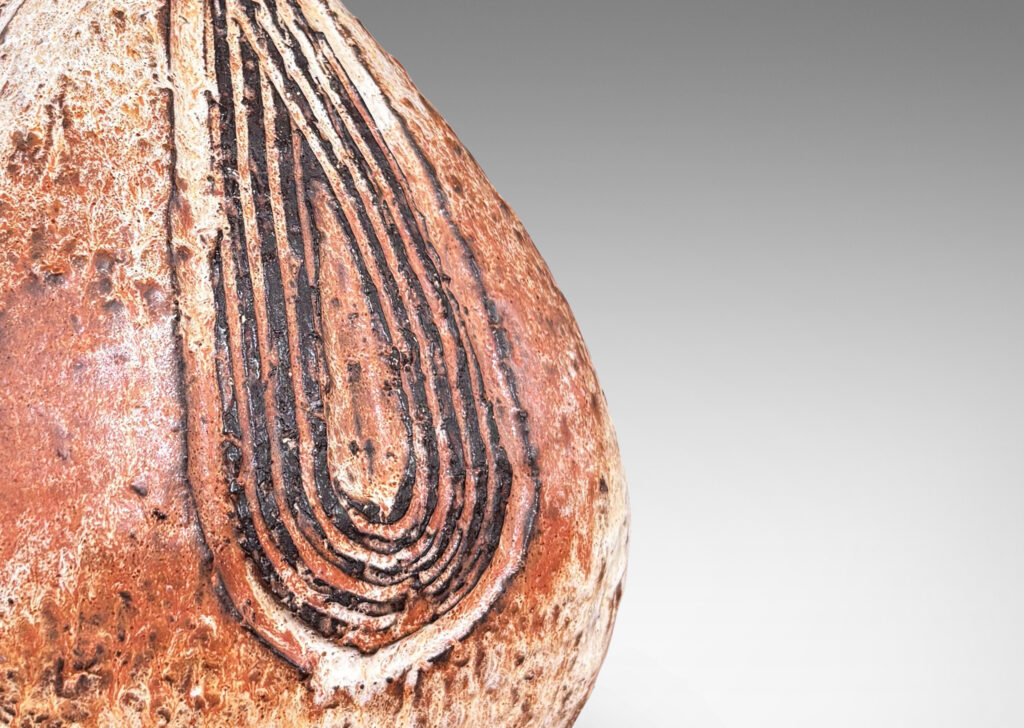 Gallery BAC squared bulb form with attenuated neck and carved concentric drop design, glazed in pale gray-tan and brown