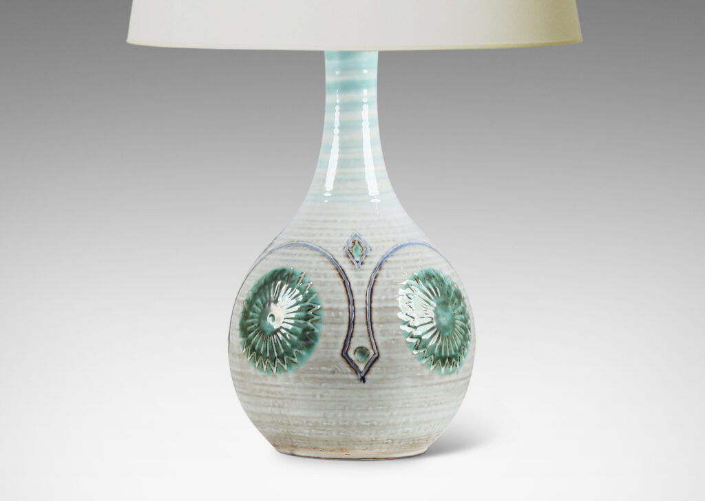 Gallery BAC globe form with tall sprouting neck, decorated with turning ridges and carved geometric folk-style ornaments, glazed in a pale gray-off white, with purple and green accent