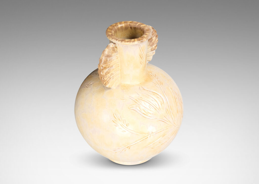 Gallery BAC globe form, with carved floral design, and neck framed by frill handles, glazed in sponged pale yellow-tan with hints of gray