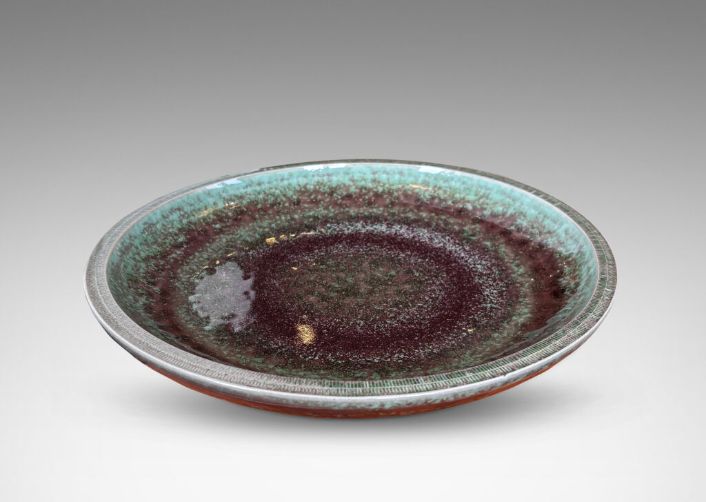 Gallery BAC beautifully sculpted wide shallow form with lip finished in carved hatch marks and a marvelous oxblood-celadon glaze