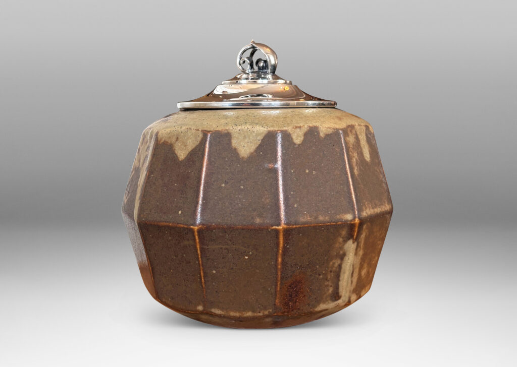 Gallery BAC angled and faceted form glazed in pale taupe-brown, with silver plated lid topped by a foliate finial