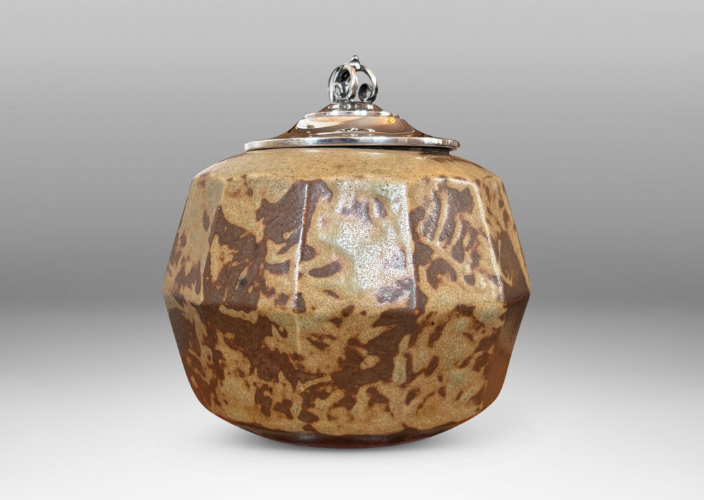 Gallery BAC angled and faceted form glazed in pale taupe-brown, with silver plated lid topped by a foliate finial