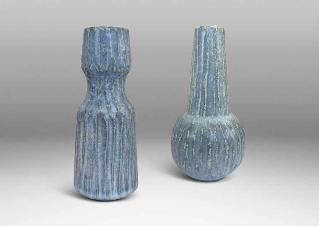 Gallery BAC notched form and another with a conical neck on a spherical body, both with carved surfaces glazed in a pale gray-blue