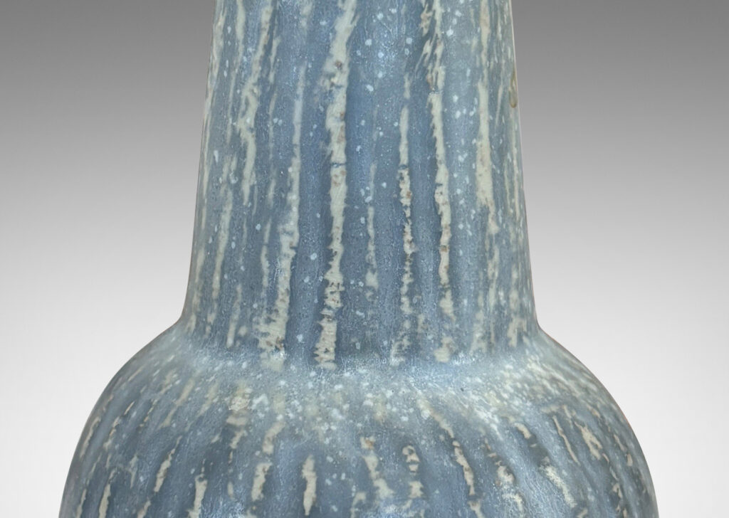 Gallery BAC notched form and another with a conical neck on a spherical body, both with carved surfaces glazed in a pale gray-blue