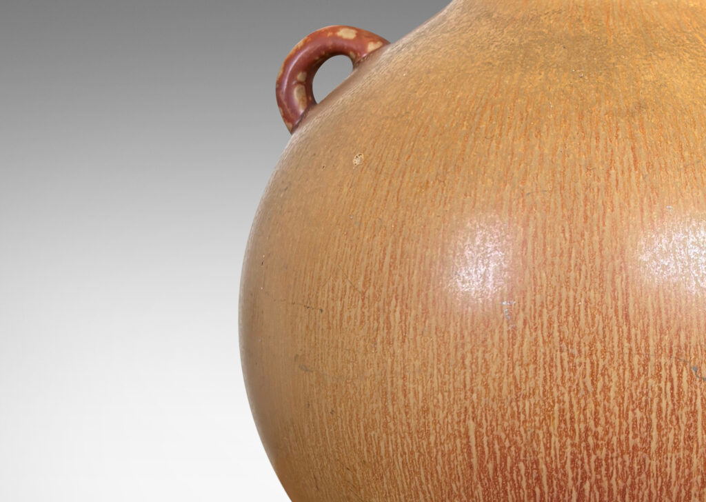 Gallery BAC globe form with sprouting neck and pair of ear-form handles, glazed in a flowing ochre tan-burnt sienna