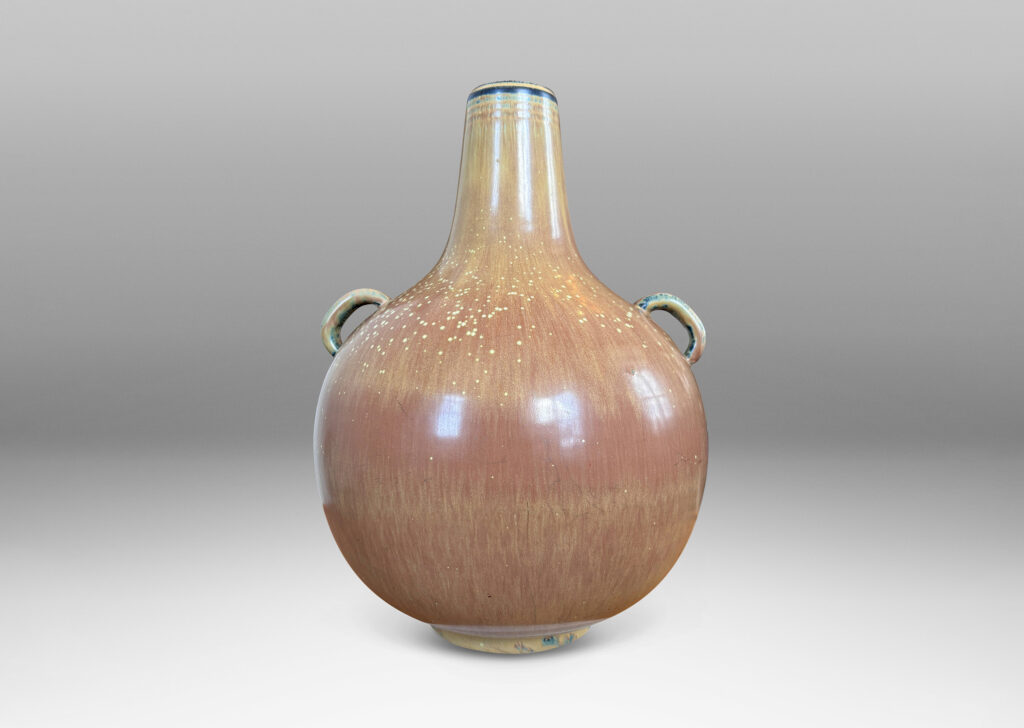 Gallery BAC globe form with sprouting neck and pair of ear-form handles, glazed in a flowing burnt sienna-ochre tan with pale speckling on shoulders