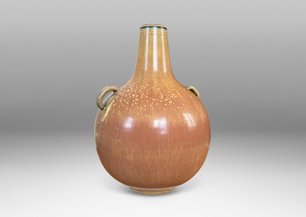 Gallery BAC globe form with sprouting neck and pair of ear-form handles, glazed in a flowing burnt sienna-ochre tan with pale speckling on shoulders