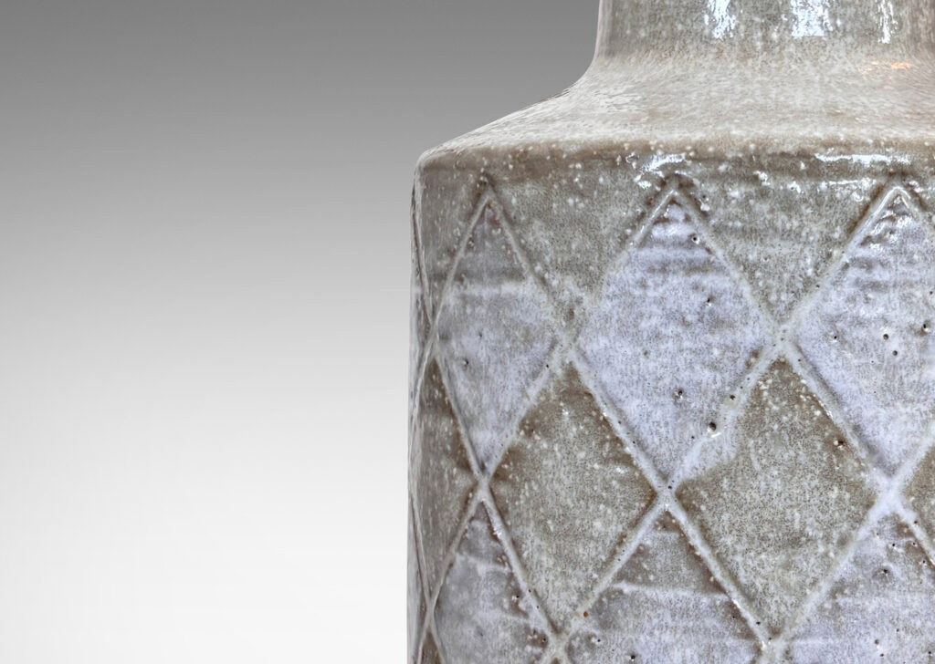 Gallery BAC drum form with carved harlequin design, and tall conical neck, glazed in pale gray with some diamond motifs in white