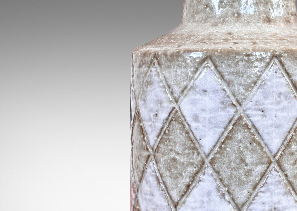 Gallery BAC drum form with carved harlequin design, and tall conical neck, glazed in pale gray with some diamond motifs in white