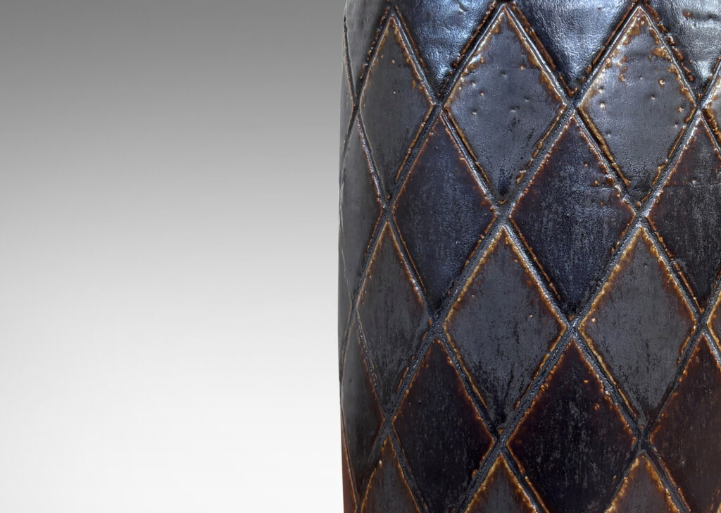 Gallery BAC drum form with carved harlequin design, and tall conical neck, glazed in eggshell brown with some diamond motifs finished in matte