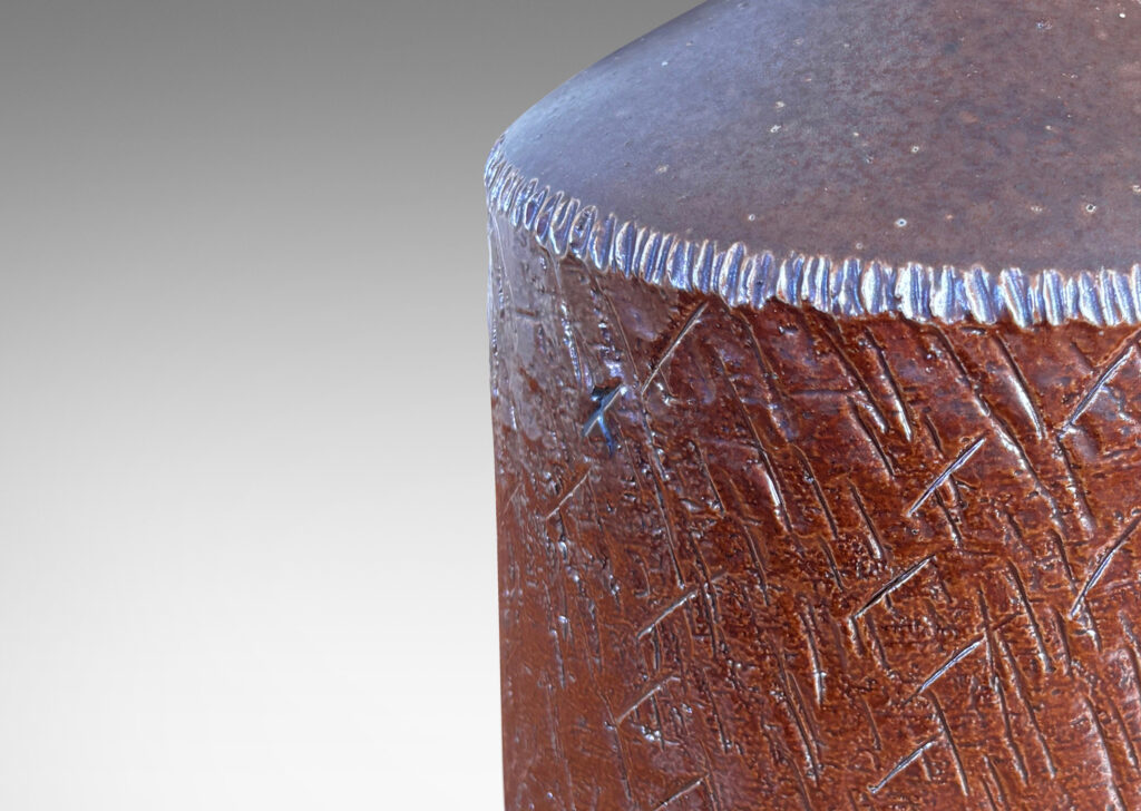 Gallery BAC drum form with encircling carved texture and whipstich pattern edging, glazed in a coppery red luster and brown