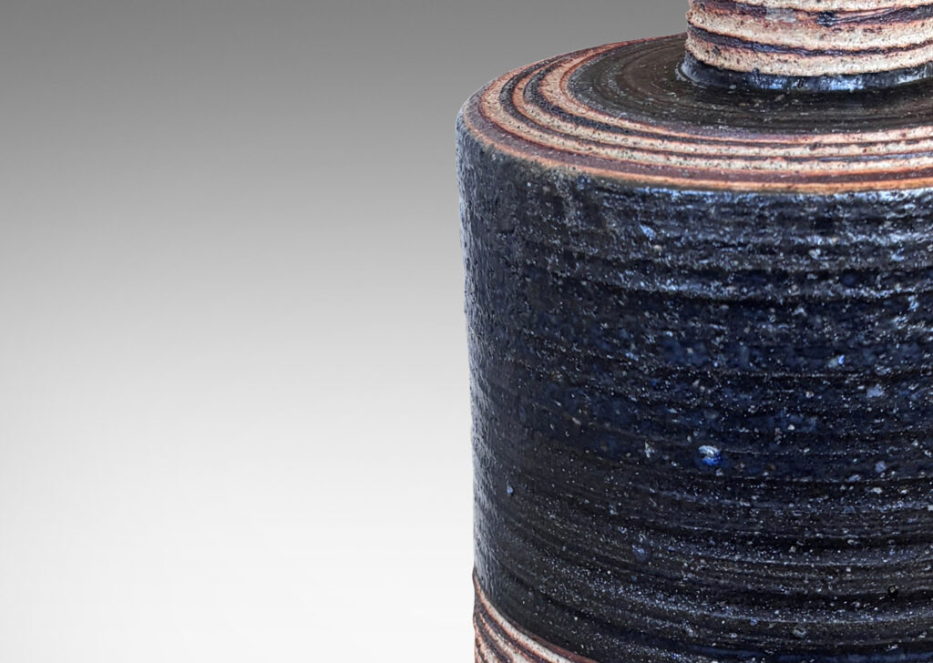 Gallery BAC slant-sided cylindrical forms with impressed texture and sprouting necks, glazed in shiny white and matte brown