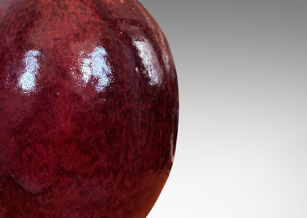 Gallery BAC ovoid form with sprouting attenuated neck, glazed in a flowing oxblood burgundy with red accents