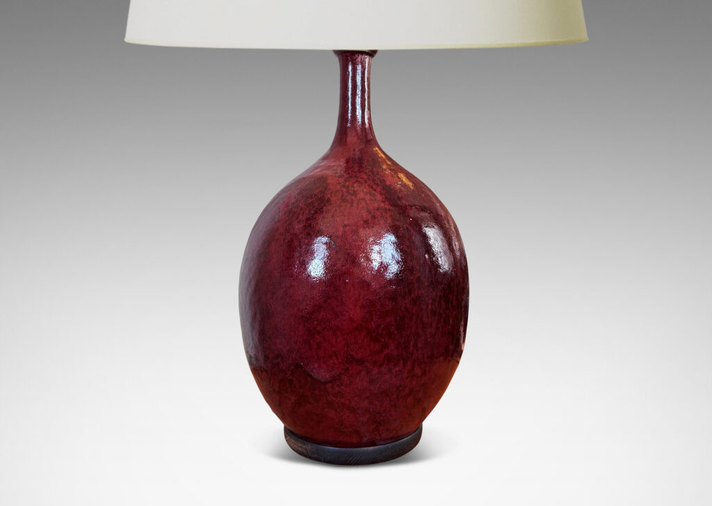 Gallery BAC ovoid form with sprouting attenuated neck, glazed in a flowing oxblood burgundy with red accents