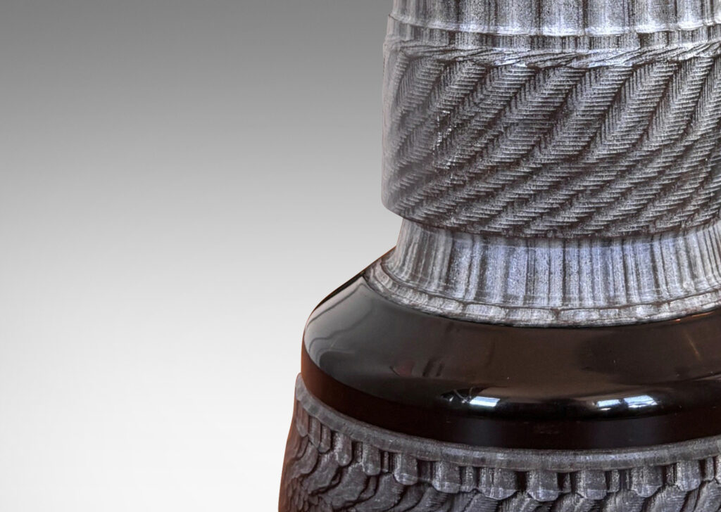 Gallery BAC totemic pillar form with turned and carved ornamental textures in a matte gray, with gloss black widened base