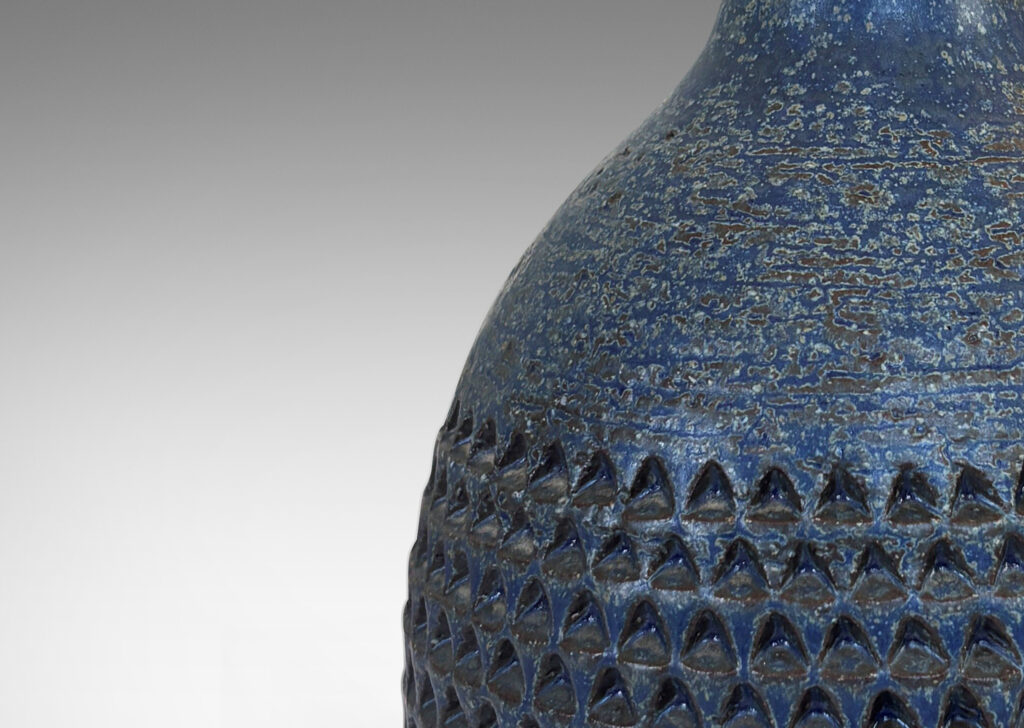 Gallery BAC bulbous form with rows of impressed triangular motifs and conical neck; glazed in a dark blue