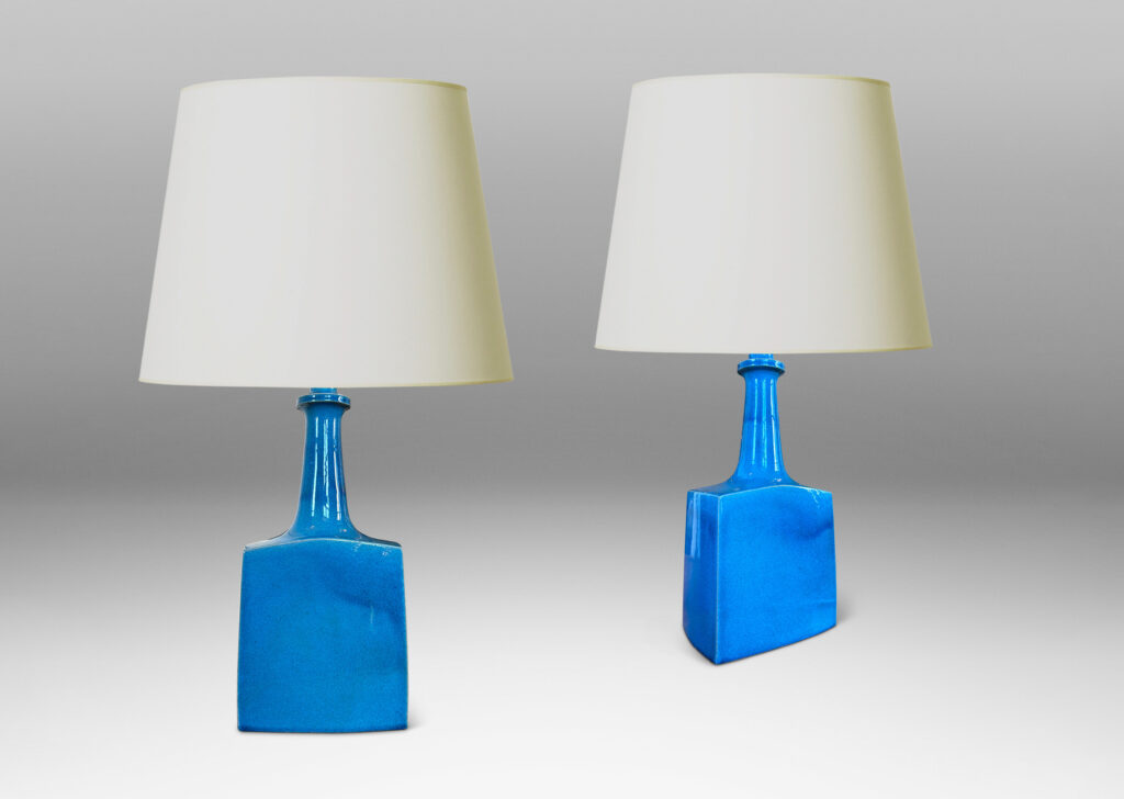 Gallery BAC bottle-like forms, having squared bases and slender sprouting necks, glazed in a saturated azure tone