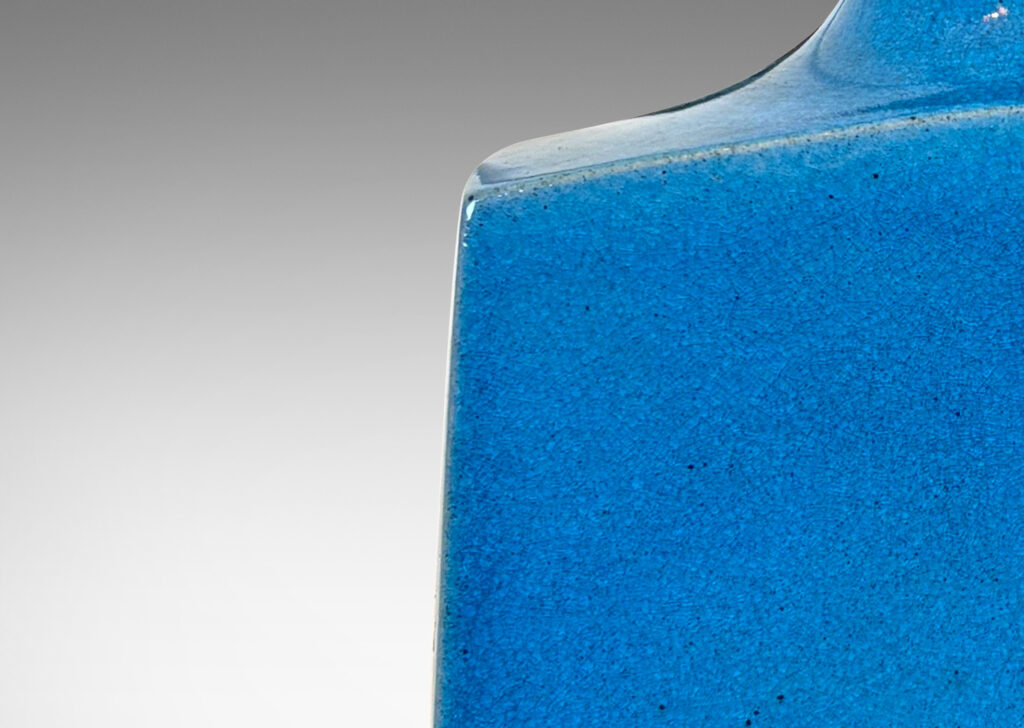 Gallery BAC bottle-like forms, having squared bases and slender sprouting necks, glazed in a saturated azure tone