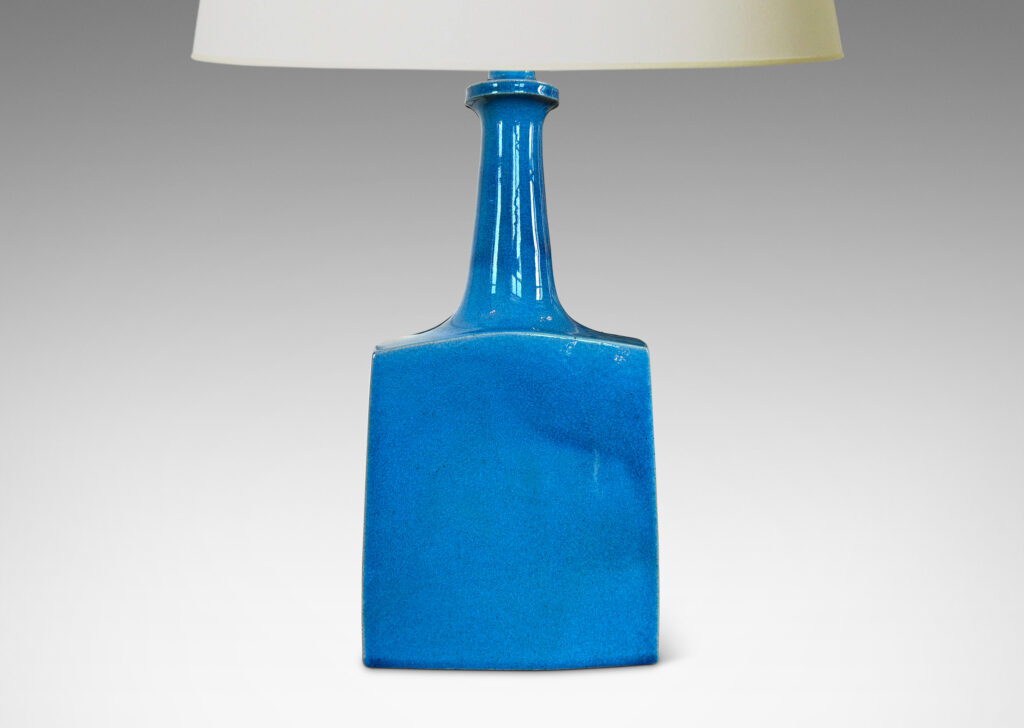Gallery BAC bottle-like forms, having squared bases and slender sprouting necks, glazed in a saturated azure tone