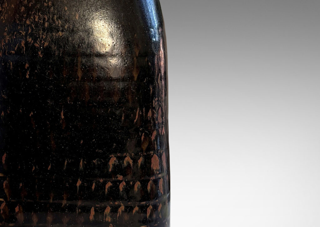 Gallery BAC tall square bottle-like form with rows impressed triangular motifs, glazed in black with hints of red luster