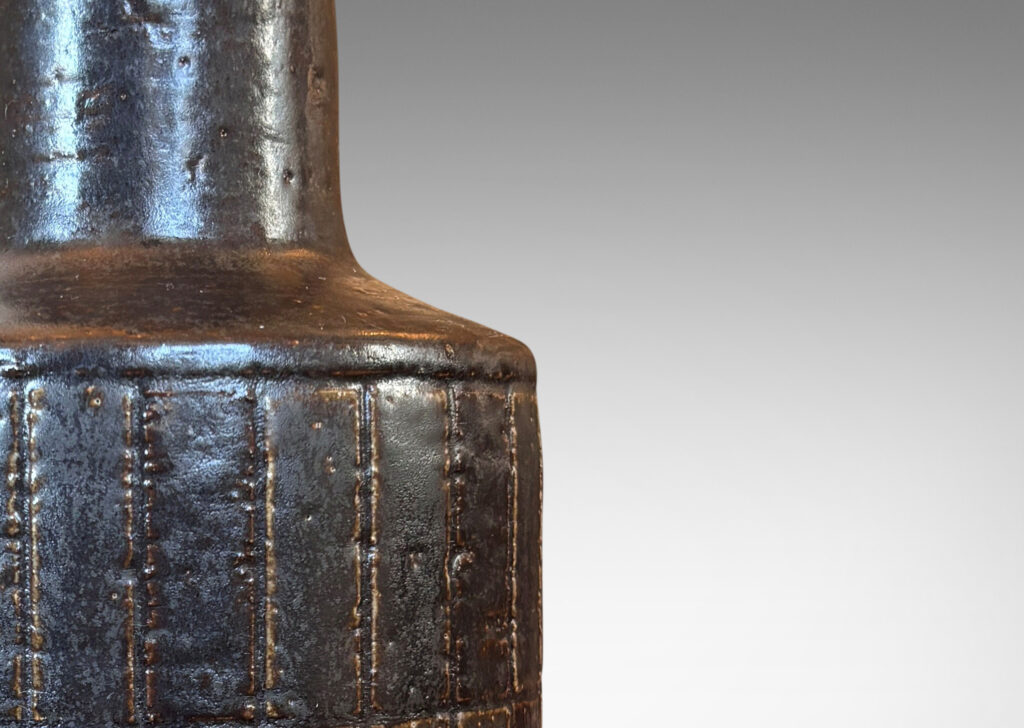 Gallery BAC drum form with carved grid design, and tall conical neck, glazed in eggshell brown with some diamond motifs