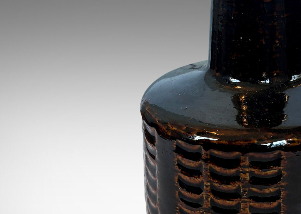 Gallery BAC drum form encircled with grids of carved arc divots and tall conical neck, glazed in a shiny dark brown