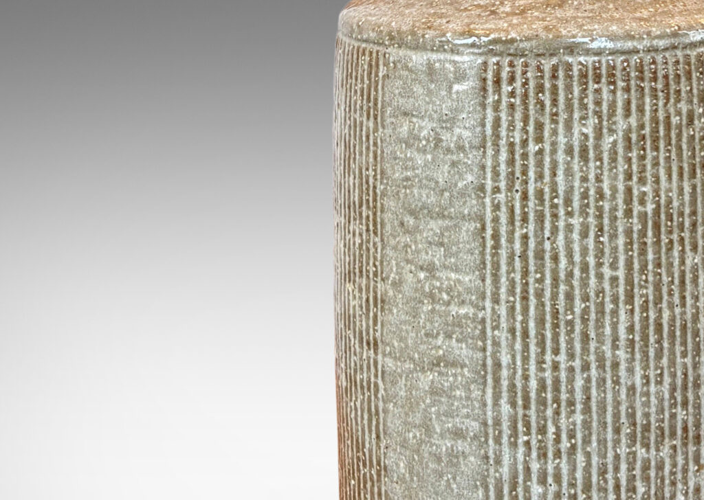 Gallery BAC drum form with carved strike design, and tall conical neck, glazed in pale taupe