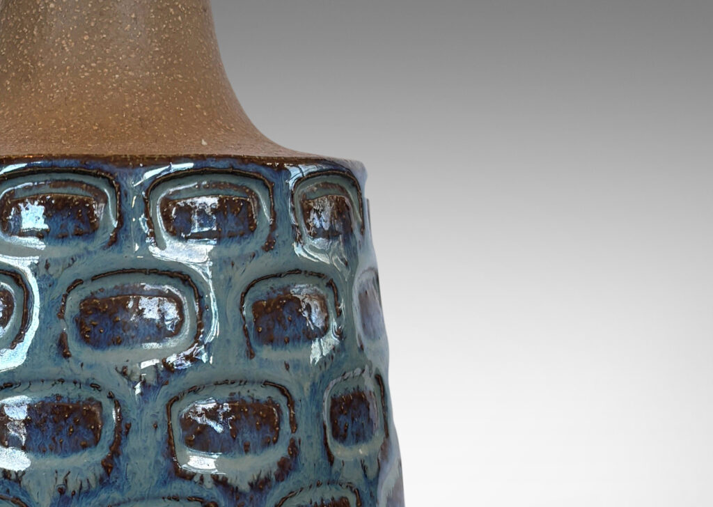 Gallery BAC raked cylinder form with impressed ovoid design and sprouting neck, partially glazed in a flowing icy pale blue