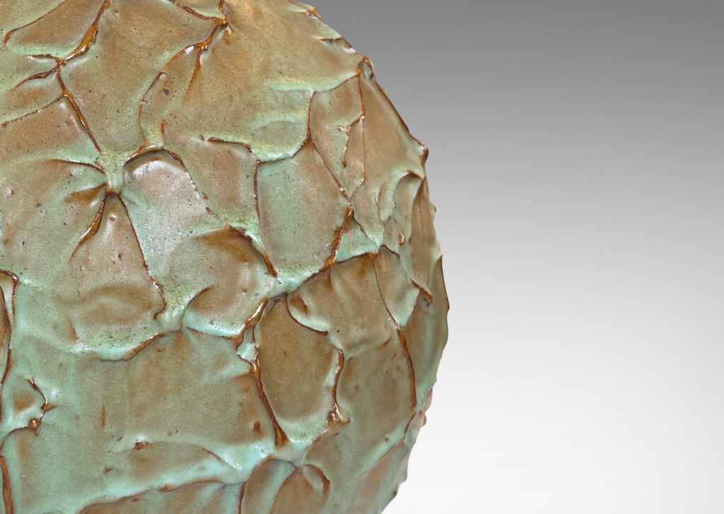 Gallery BAC highly textured globe form in a bright celadon glaze with brown tinted edges from the underlying ceramic