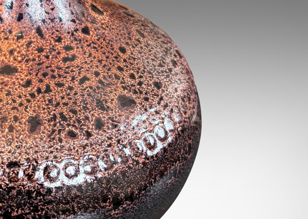 Gallery BAC low wide bulbous form with relief ring of dots; glazed in dark brown with a frothy effect on shoulders