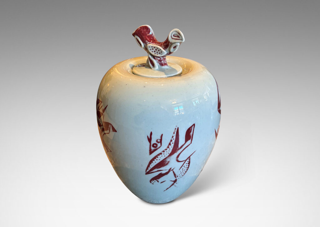 Gallery BAC tapered form and lid with branch-like finial, glazed in celadon with hand-painted abstracted fish, plants, shells and patterning in oxblood