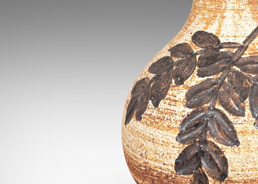 Gallery BAC swelling form with flared neck, with grog texture and carved foliate design, glazed in a pale golden beige with medium brown dry brush striae texture and dark brown decoration