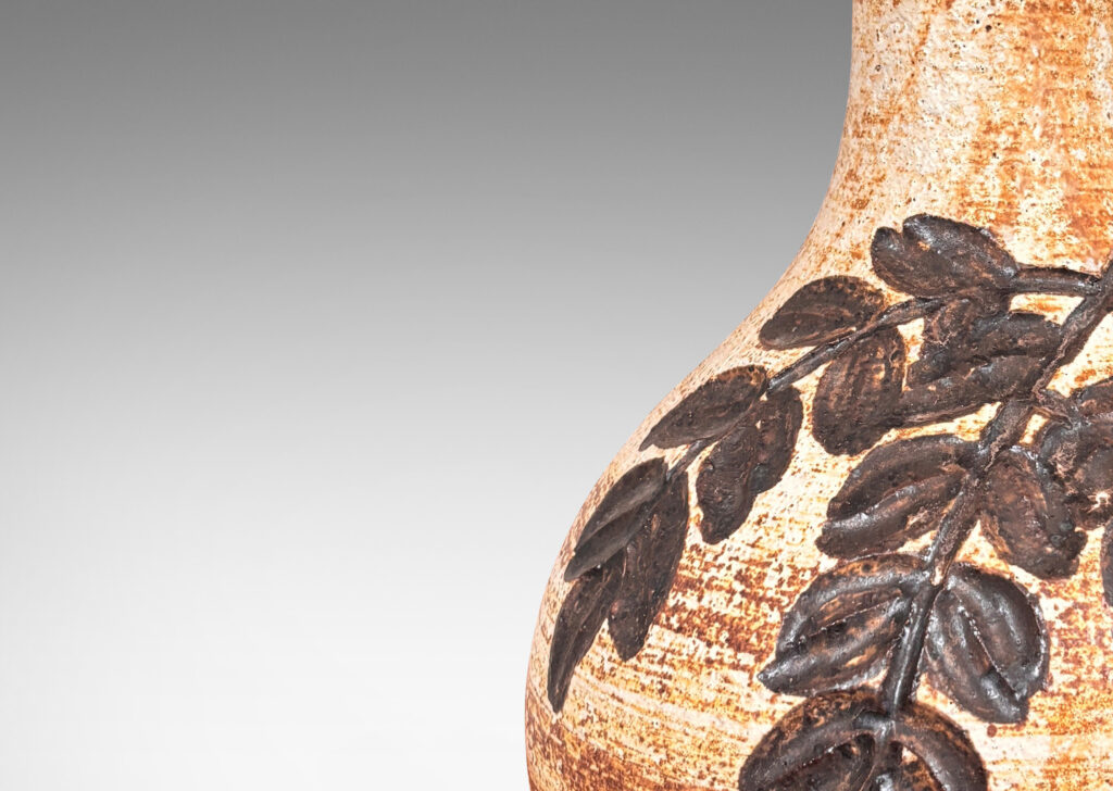 Gallery BAC swelling form with flared neck, with grog texture and carved foliate design, glazed in a pale golden beige with medium brown dry brush striae texture and dark brown decoration