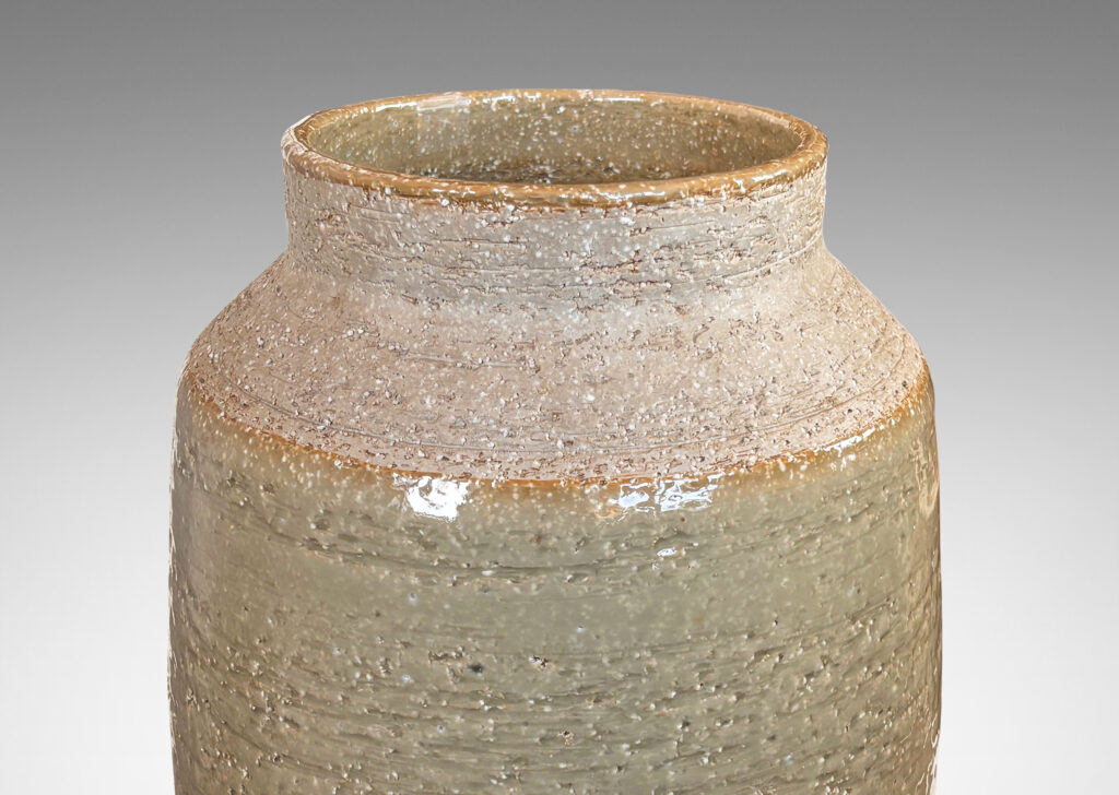 Gallery BAC swelling cylindrical form with angled shoulder and wide cuff mouth in grog ceramic with partial gloss greenish gray gloss