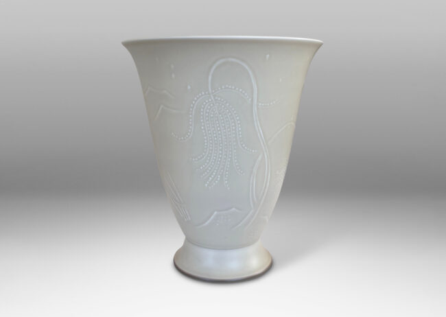 Gallery BAC lyre-form silhouette on a flanged stand, surrounded in stylized scenery in relief, glazed in a very pale gray