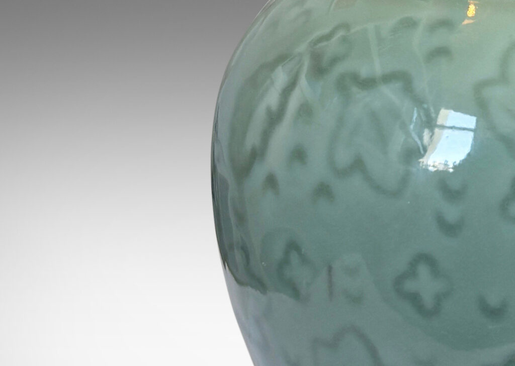 Gallery BAC apered globe form with coved neck, with carved floating leaf motifs, glazed in a thick ethereal celadon green