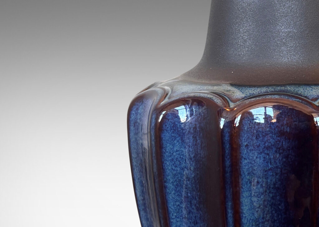 Gallery BAC pawn-like forms with a fluted drum body and conical neck, glazed in a gloss blue luster and matte brown