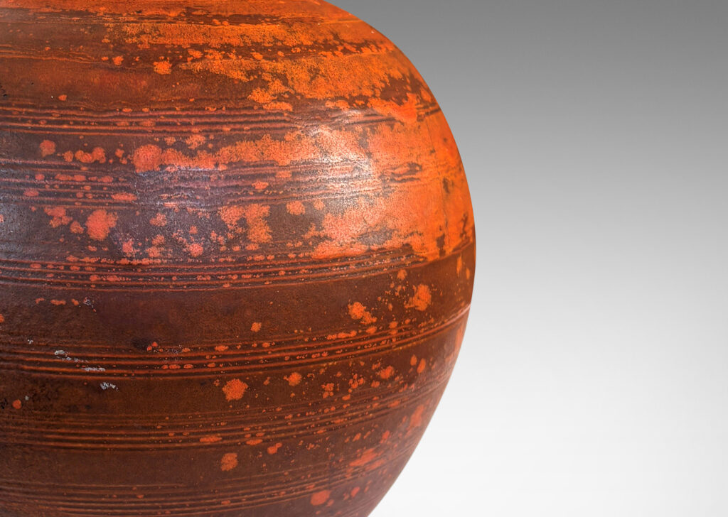 Gallery BAC globe form with carved pinstripe banding, glazed in matte orange and burnt orange brown