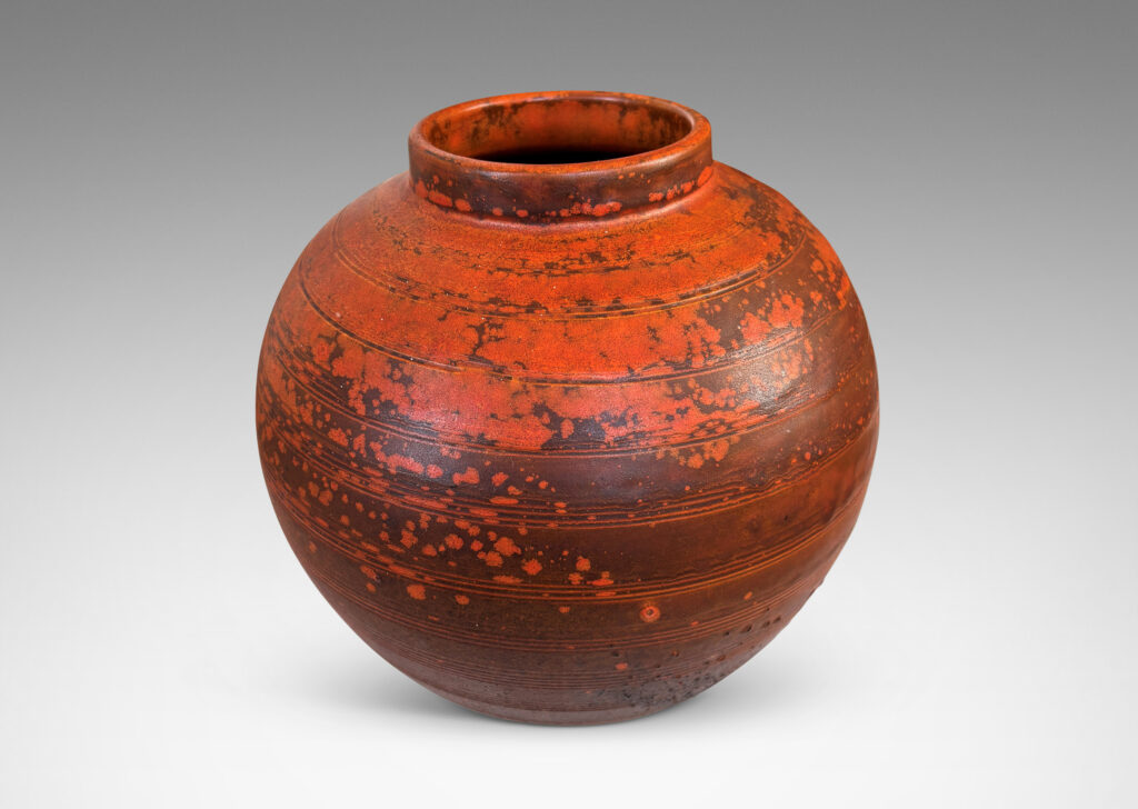 Gallery BAC globe form with carved pinstripe banding, glazed in matte orange and burnt orange brown
