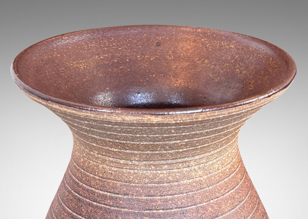 Gallery BAC tall swelling form with flared mouth and carved pinstripe spiral, partially glazed inside with an eggshell finish brown