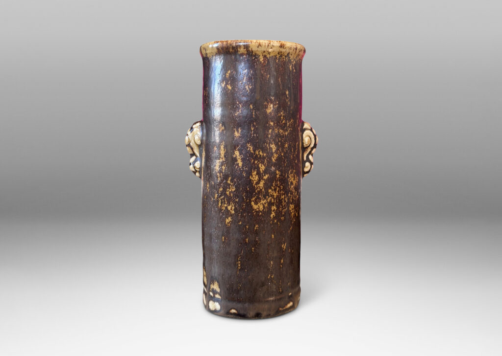 Gallery BAC cylindrical form with articulated lip and stylized floral handles, glazed in brown over pale tan