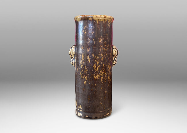 Gallery BAC cylindrical form with articulated lip and stylized floral handles, glazed in brown over pale tan