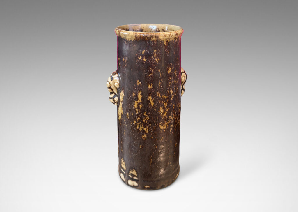 Gallery BAC cylindrical form with articulated lip and stylized floral handles, glazed in brown over pale tan