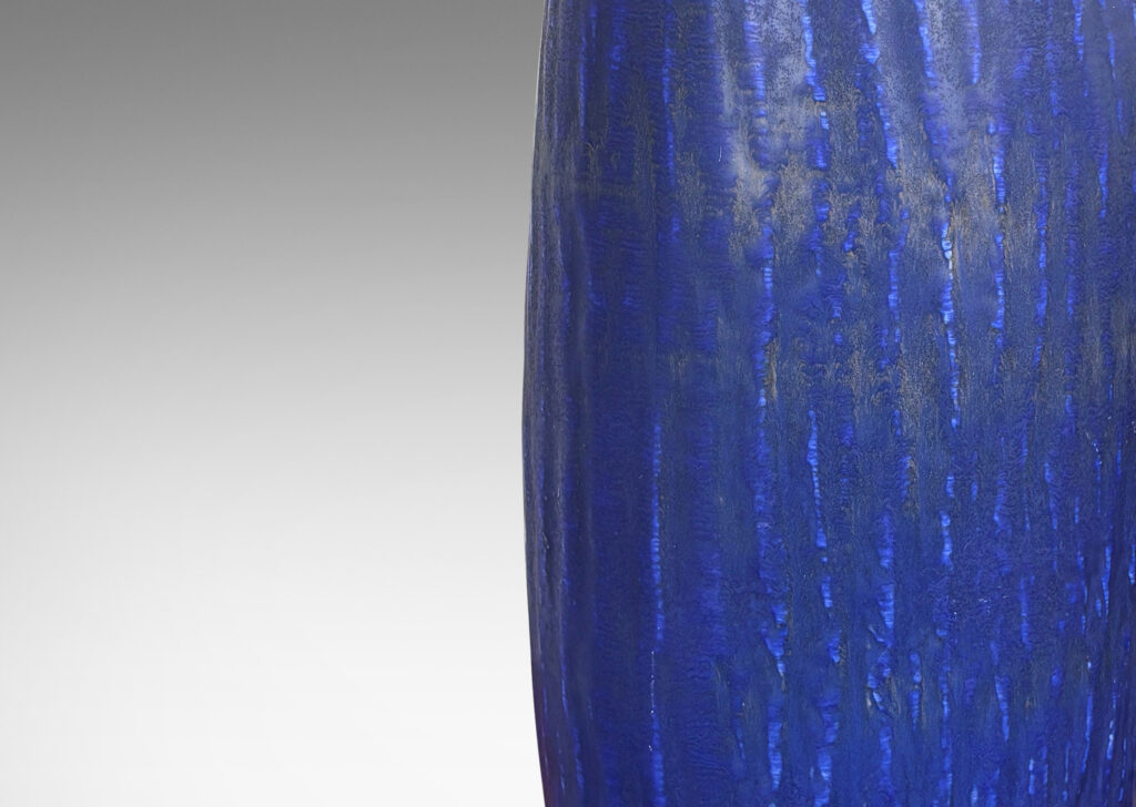 Gallery BAC swelling cylindrical form with carved gouged surface and flowing deep blue over brown glazing