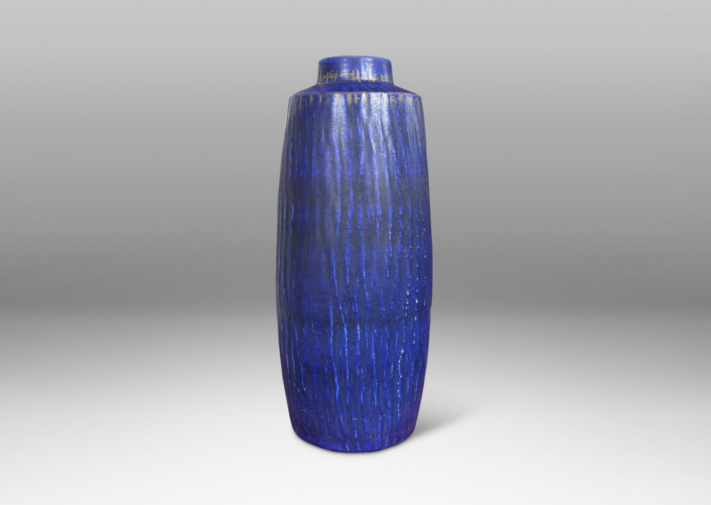 Gallery BAC swelling cylindrical form with carved gouged surface and flowing deep blue over brown glazing