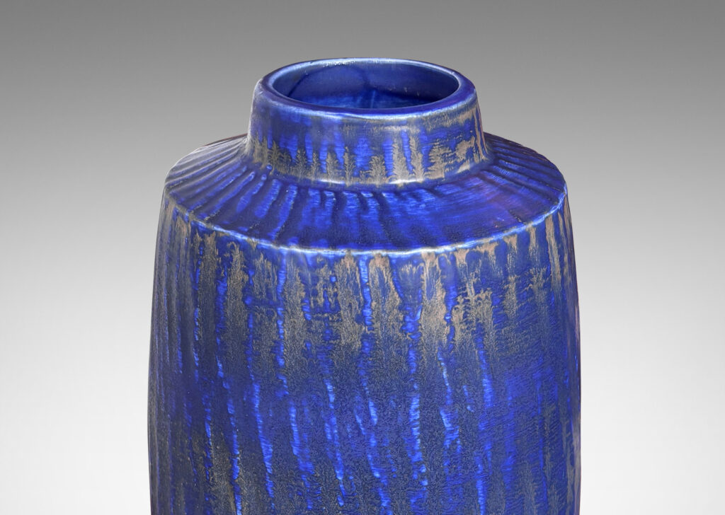 Gallery BAC swelling cylindrical form with carved gouged surface and flowing deep blue over brown glazing