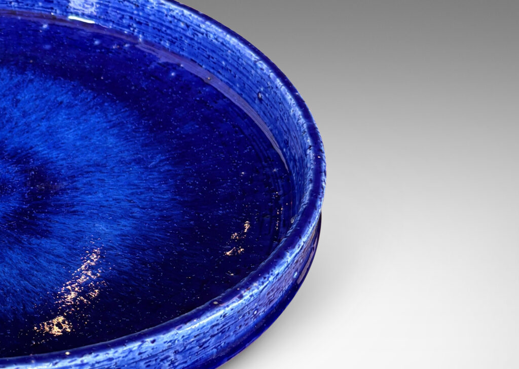Gallery BAC wide concave form with shallow straight sides, in textured chamotte with a saturated blue glaze