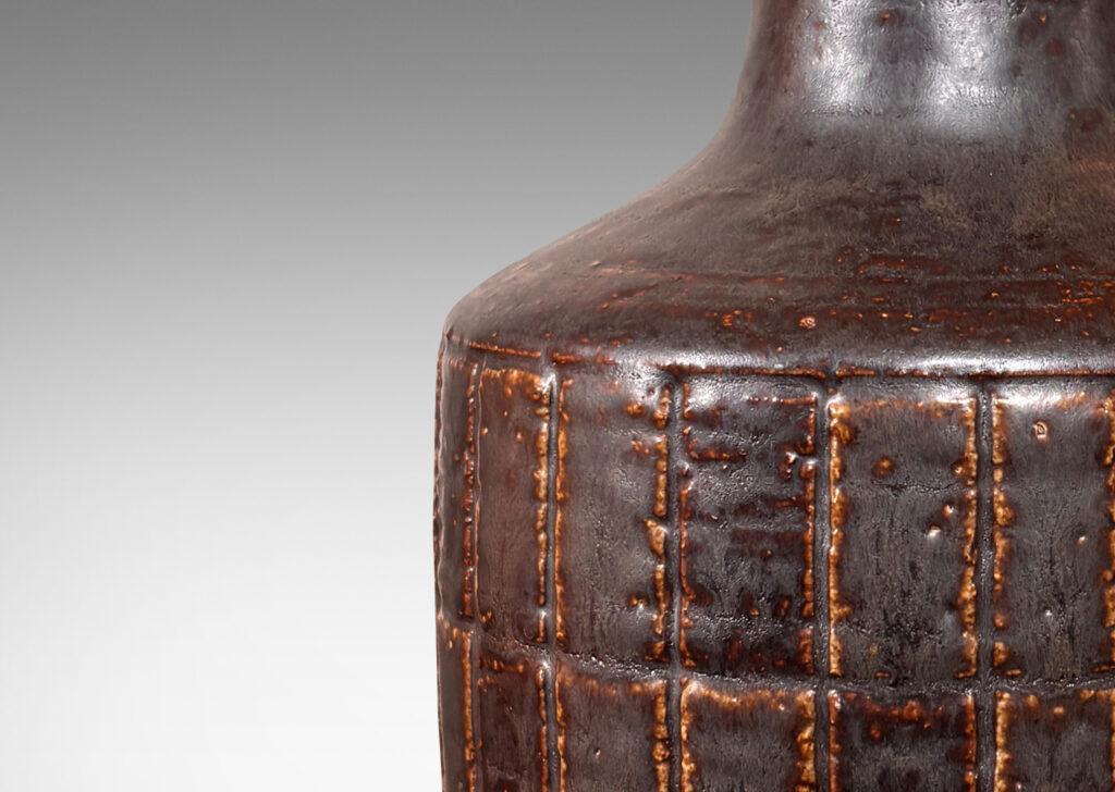 Gallery BAC low drum form with carved grid pattern, tall conical neck, and matte brown glaze