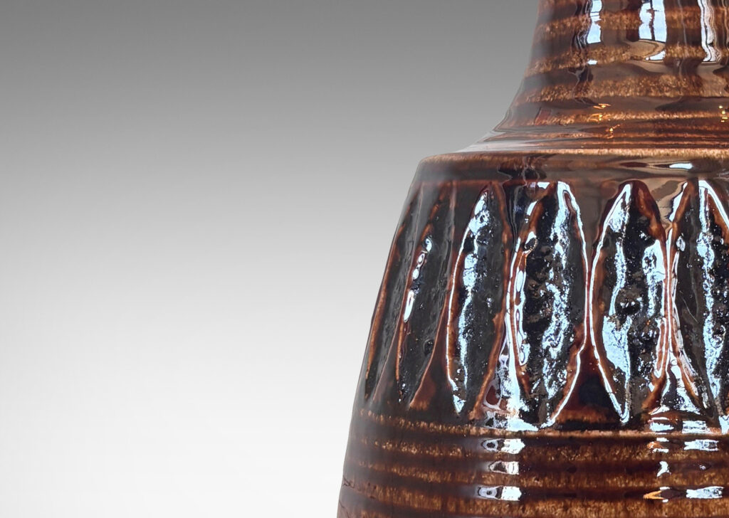 Gallery BAC pawn-like form with ridged texture, band of carved ovoids, and sprouting neck, glazed in a glossy brown